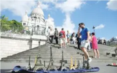  ?? — Reuters ?? A tourist walks past Eiffel Tower models in front of Montmartre's Sacre Coeur Church in Paris.