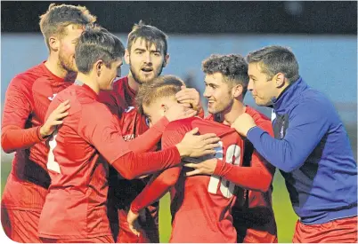  ??  ?? Brora team-mates congratula­te Andy Macrae (No. 10) on scoring against Buckie