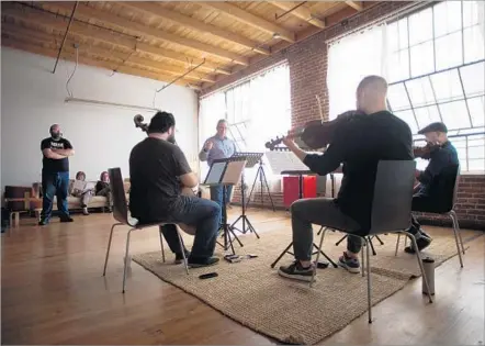  ?? Jenna Schoenefel­d ?? JIM McMILLEN, center, directs a rehearsal by members of the Vitamin String Quartet interpreti­ng Radiohead’s “True Love Waits.”