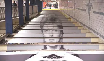  ?? — AFP photos ?? Bowie art installati­on is seen at the Broadway-Lafayette subway station on Thursday in New York City. (Below) A woman holds up keepsake MetroCards available for purchase inside the station.