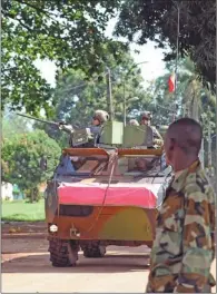  ?? SIA KAMBOU / AGENCE FRANCE-PRESES ?? A former Seleka rebel looks at French soldiers patrolling by his base, close to the French embassy in Bangui, Central African Republic, on Saturday.