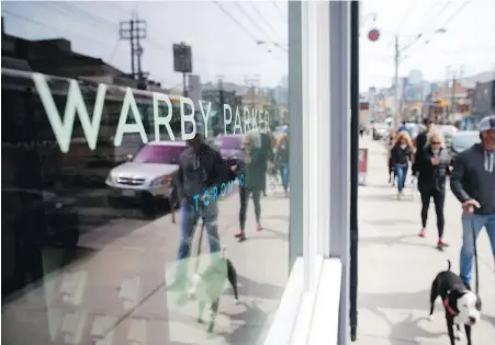  ??  ?? People walk by U.S.-based eyewear boutique Warby Parker’s Toronto store on Queen Street in Toronto on Sunday.