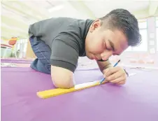  ?? ?? Abdullah measures fabric he had purchased to turn it into curtains for his classroom. — Bernama photo