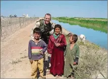  ?? COURTESY OF DAN NEVINS ?? Dan Nevins with Iraqi children near Balad, where he was stationed in 2004.