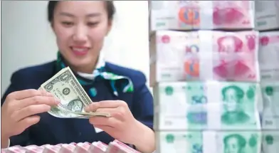  ?? ZHANG YUN / CHINA NEWS SERVICE ?? A clerk counts cash at a bank in Taiyuan, capital of Shanxi province.
