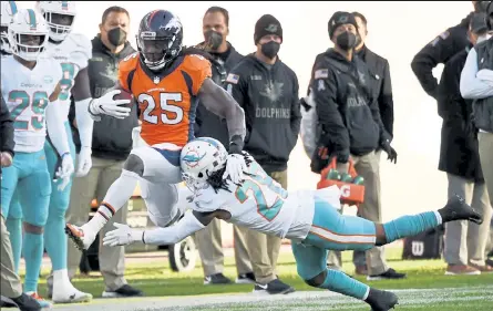  ?? Andy Cross / The Denver Post ?? Broncos running back Melvin Gordon high steps over Dolphins strong safety Bobby Mccain during Sunday’s game at Empower Field at Mile High in Denver.