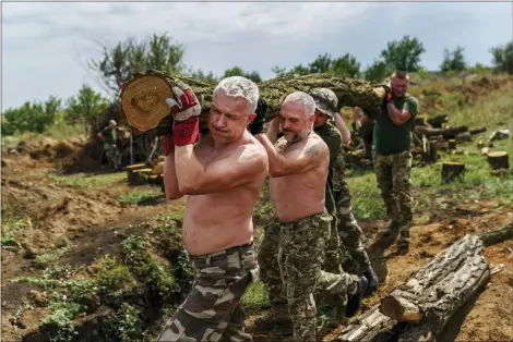  ?? DAVID GOLDMAN-ASSOCIATED PRESS ?? Members of the Dnipro-1regiment carry logs to fortify their position near Sloviansk, Donetsk region, eastern Ukraine, Friday.