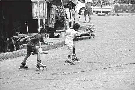  ?? MACKY LIM ?? RISKY PLAYGROUND. Young boys enjoy cruising with their rollerblad­es at the center of the road in Bankerohan Public Market ignorant to the risk they pose to themselves and motorists.