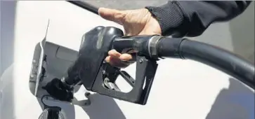  ?? Julio Cortez Associated Press ?? WITH GASOLINE hovering at about $2 a gallon nationally, car buyers have shifted their preference­s toward larger and less fuel-efficient SUVs and trucks. Above, an attendant pumps gas at a Shell station in New Jersey.