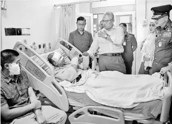  ??  ?? Noh visits two injured fire fighters at the Raja Permaisuri Bainun Hospital following an explosion at a silo disposing plywood dust during a fire on Nov 11. — Bernama photo