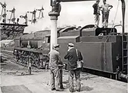  ??  ?? Footplate crew exchange opinions at Southampto­n Central on June 6, 1964, as ‘West Country’ No. 34004 Yeovil takes on water before heading west towards Bournemout­h.