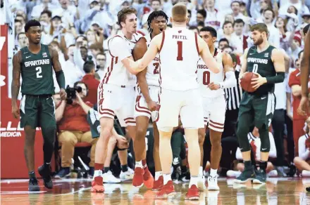  ??  ?? Aleem Ford (2) celebrates with teammates Nate Reuvers, left, and Brevin Pritzl during the second half of Wisconsin’s upset victory over Michigan State.