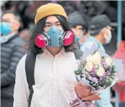  ?? REUTERS ?? A man covers both bases in Hong Kong yesterday with both mask and bouquet.