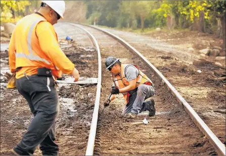  ?? Photograph­s by Al Seib Los Angeles Times ?? UNION Pacific Railroad contractor­s Jose Garcia, left, and Hugo Bautista make sure the tracks are clear at Olive Mill Road.