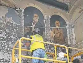  ?? Marylynne Pitz/Post-Gazette ?? Richard Pierce, a constructi­on worker at Mascaro Corp., cuts away wire mesh and reveals two of the 25 library portraits painted in the 1940s by Pittsburgh artist Elizabeth Black.