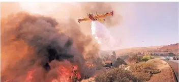  ?? FOTO: DPA ?? Ein Löschflugz­eug ist bei einem Brand am Ronald Reagan Freeway im Einsatz. Gewaltige Brände im Norden und Süden Kalifornie­ns haben Hunderte Quadratkil­ometer Wald vernichtet.