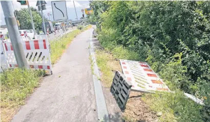  ?? NGZ-FOTO: ANJA TINTER ?? Absperrgit­ter und Verbotssch­ilder liegen im Gebüsch: An der Neersener Straße bahnen sich viele Fußgänger und Radfahrer einfach ihren Weg. Auch die Autofahrer verhalten sich oft falsch, biegen an der Ohrenbrück­e immer wieder verbotswid­rig ab.