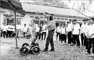  ??  ?? David MacMillan, an expert from SparrowHaw­k Far East company, operating the ground-penetratin­g radar machine while teachers and students look on during a search for mass graves at a school compound in Prey Veng province. — AFP photos