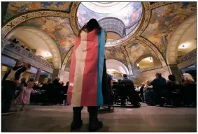  ?? (AP/Charlie Riedel) ?? Glenda Starke wears a transgende­r flag as a counter protest during a rally in favor of a ban on gender-affirming health care legislatio­n in March at the Missouri Statehouse in Jefferson City. A Missouri judge said Friday that a law banning gender-affirming treatments for minors can take effect Monday.