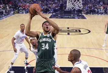  ?? SHOOT. (AP)* ?? Milwaukee Bucks forward Giannis Antetokoun­mpo, second from right, shoots as Los Angeles Clippers center Serge Ibaka, right, defends during the first half of an NBA basketball game Sunday, Feb. 6, 2022, in Los Angeles.