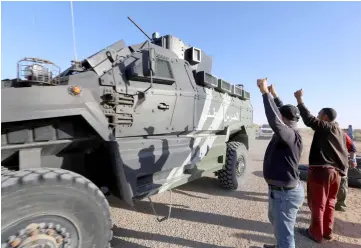  ??  ?? Tunisian men salute National Guard forces in the southern Ben Guerdane region after they exchanged fire and shot two men suspected of belonging to a jihadist group. — AFP photo