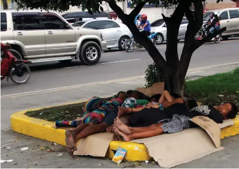  ?? JOY TORREJOS ?? TRAFFIC HAZARD. Street kids take a nap at the sidewalk along a Mandaue City highway, unmindful of the noise and the danger of vehicles speeding past.