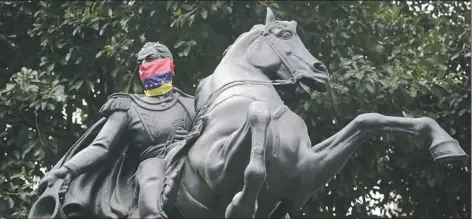  ?? Wil Riera/Associated Press ?? A statue of Venezuelan military leader Simon Bolivar with a mask made with the Venezuelan flag is seen last week at Chacao square in Caracas, Venezuela.