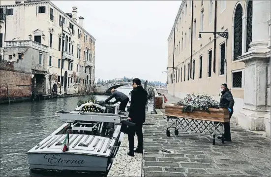  ?? MARCO DI LAURO / GETTY ?? Unos empleados públicos retiran un féretro de un hospital público en Venecia