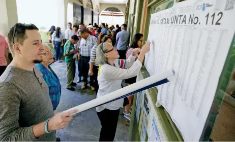  ??  ?? Ciudadanos de Costa Rica buscaban sus nombres en la lista de votantes en una de las mesas, para poder sufragar en el proceso electoral de ayer, en el que eligieron entre 13 candidatos a la presidenci­a. Según los primeros datos, la participac­ión en los...