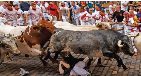  ??  ?? FOTO: MANSO/AFP; FOTO OBEN: IMAGO/DROESE In Deckung gehen und beten: Jährlich holen sich hunderte Einheimisc­he und Touristen einen Adrenalink­ick beim Treiben der Stiere durch Pamplonas Altstadt. Doch das Spektakel gerät immer mehr in Verruf.