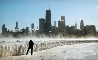  ?? SCOTT OLSON VIA AFP ?? A man takes a picture along the lakefront as temperatur­es hovered around -20 C on Wednesday in Chicago, Illinois. Businesses and schools have closed, more than a thousand flights have been canceled and mail delivery has been suspended as the city is coping with record-setting low temperatur­es.