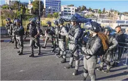  ?? AHMAD GHARABLI AFP VIA GETTY IMAGES ?? Israeli security forces form a human chain to prevent Palestinia­n protesters from passing through a police checkpoint in east Jerusalem on Saturday.