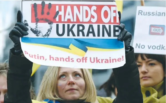  ?? (Yves Herman/Reuters) ?? PEOPLE GATHER outside a European Union emergency foreign ministers meeting in Brussels in 2014, to protest against Russian troops in Ukraine. We need to internaliz­e that this is not Russia’s first seizure of territory – remember Crimea in 2014.