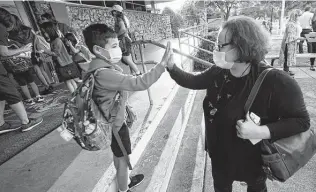  ?? LM Otero / Associated Press ?? Maksim Mongayt, 7, gives his mother Alexandra a high-five before entering his elementary school on the first day of classes in Richardson last week.