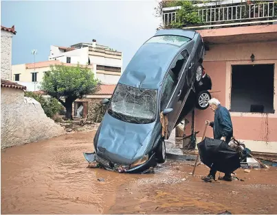  ??  ?? WRECKED: Two cars are left piled up against a house in Mandra, the area worst hit by the flash floods
