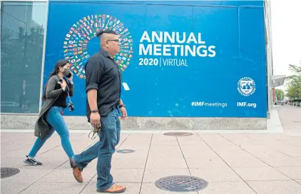  ?? AFP ?? People walk past a promotiona­l poster for the virtual 2020 Annual Meetings outside the Internatio­nal Monetary Fund’s headquarte­rs in Washington, D.C. on Tuesday.