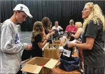  ??  ?? Members of Discover Point Church in Kettering pack meals at the Nutter Center to give local children in backpack meal programs.