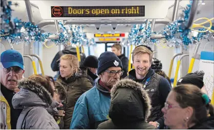  ?? MATHEW MCCARTHY WATERLOO REGION RECORD ?? Above: People squeeze onto an Ion train at the Kitchener City Hall stop during a special preview on Saturday. Left: The brand-new train gets admiring glances as it pulls into the City Hall stop.