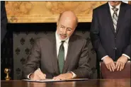  ?? MARC LEVY - THE ASSOCIATED PRESS ?? Pennsylvan­ia Gov. Tom Wolf signs an executive order for his administra­tion to start working on regulation­s to bring Pennsylvan­ia into a nine-state consortium that sets a price and limits on greenhouse gas emissions from power plants, Thursday, Oct. 3 in Harrisburg.
