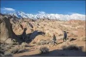  ??  ?? AGAINST the scenic backdrop of snow-capped Mt. Whitney, L.A. residents Paula Lee and Johnson Gong hike in the Alabama Hills west of Lone Pine.