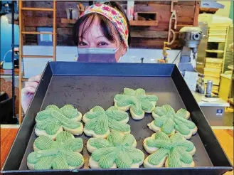  ?? NICK GRAHAM / STAFF ?? Stephanie Kyoto, manager at Almond Sisters Bakery, displays some of the Shamrock cookies that were being sold Wednesday to mark St. Patrick’s Day.