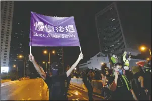  ?? The Associated Press ?? UMBRELLA RIVERS: A demonstrat­or holds up a sign reading “Back away slowly” to encourage other demonstrat­ors to leave, near the Chinese Liaison Office in Hong Kong, Sunday. Protesters turned Hong Kong streets into rivers of umbrellas Sunday as they marched through heavy rain from a packed park and filled a major road in the Chinese territory, where mass pro-democracy demonstrat­ions have become a regular weekend activity this summer.