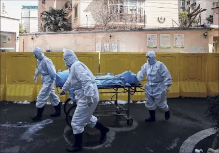  ?? Associated Press ?? Medical workers move a person who died Feb. 16 from COVID-19 at a hospital in Wuhan, China.