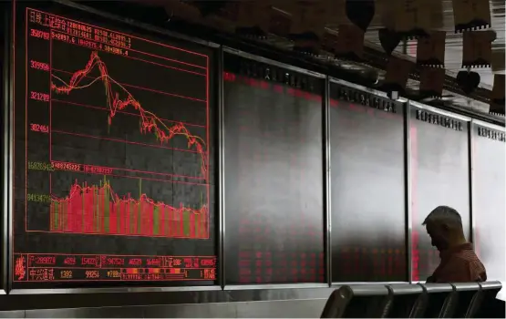  ?? — AP ?? Market support:A man sits in front of an electronic board displaying stock prices at a brokerage in Beijing. Analysts say China’s so-called National Team with more than 1 trillion yuan (US$145bil) in assets under management may already be propping up the market.