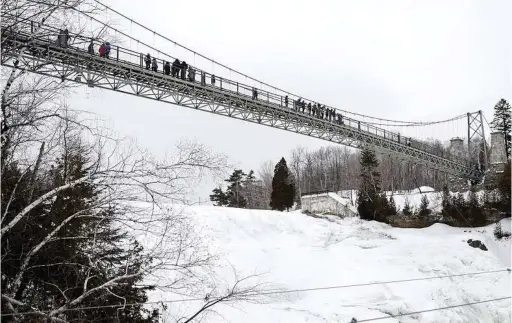  ??  ?? A bridge takes visitors over Montmorenc­y Falls, at 272 feet, a waterfall (only partially frozen in winter) taller than Niagara Falls.