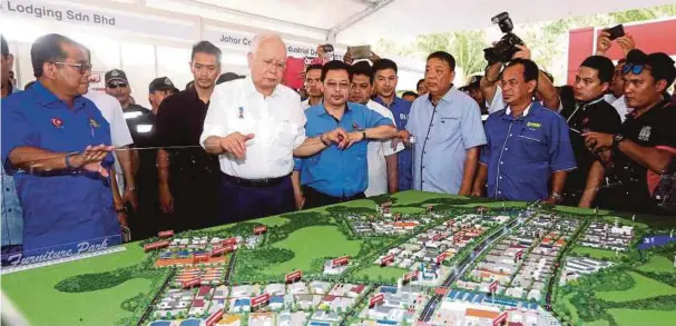  ?? FOTO: ?? NAJIB diiringi Mohamed Khaled (kiri) melihat pelan Muar Furniture Park yang dilancarka­n semalam.