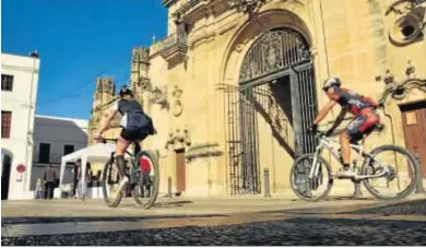  ?? RAMÓN AGUILAR ?? Dos ciclistas paseando este puente por la Plaza del Cabildo, junto a la iglesia de Santa María, en Arcos.