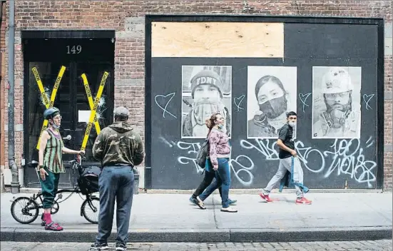  ?? MARK LENNIHAN / AP ?? Una calle en el Soho de Nueva York, con cristales rotos en los comercios e imágenes de trabajador­es esenciales