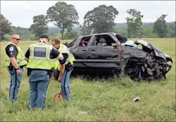  ??  ?? ABOVE: Floyd County police officers John Glaze (from left), Jim McCormick and Chad Matthews compare notes after rescue personnel evacuated the driver of the Toyota Tundra which veered off US 411 East between Nichols Road and the Spring Creek Bridge.