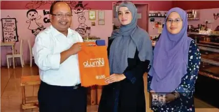  ?? [Foto ihsan Alumni UMS] ?? Dayang Irme menerima cenderamat­a daripada Mohd Raffie sempena Program Jejak Alumni anjuran Pusat Kerjaya dan Alumni UMS, di kedainya di Kota Kinabalu.